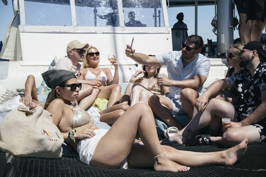 Lisbon: Catamaran Boat Party with Music, Open Bar & Dives - Getting into the Tagus from the ladder