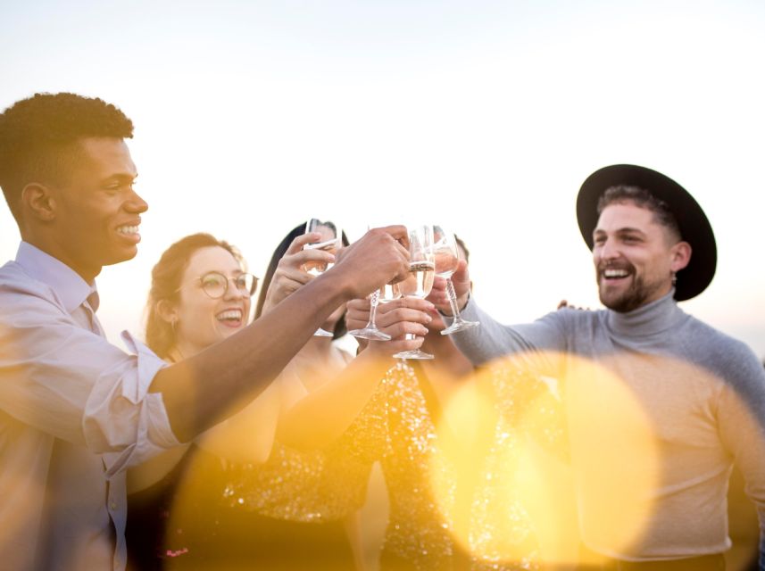 Three passengers raising glasses on the deck of a Lisbon sunset party cruise